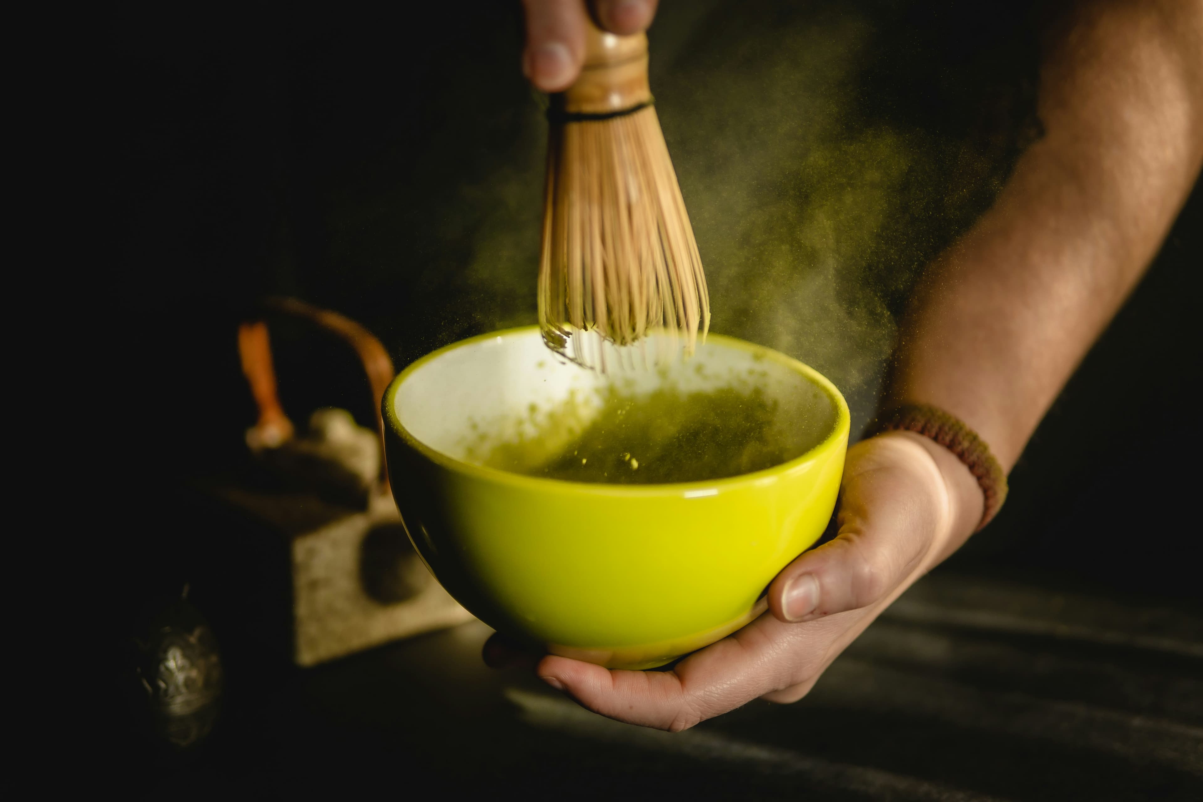 黄色の陶器の茶碗で抹茶を点てる手元 (※イメージ写真)