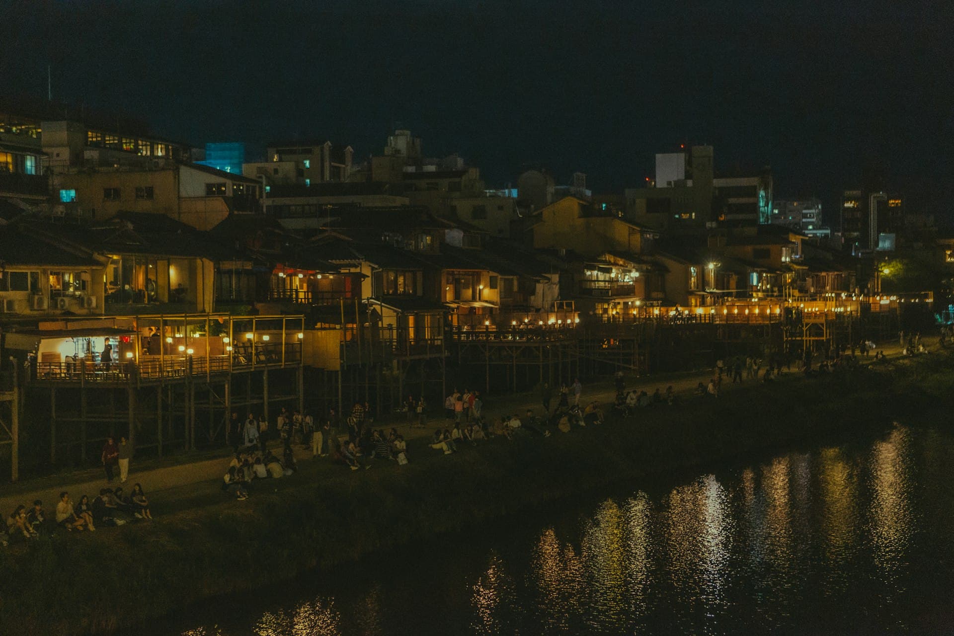 灯りの灯った納涼床と鴨川沿いに集う人々の夜景 (※イメージ写真)